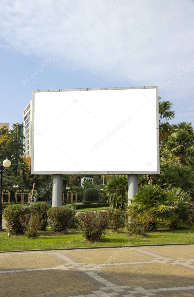 Blank street billboard poster in the park on the background of tropical plants. information banner, copy space for text