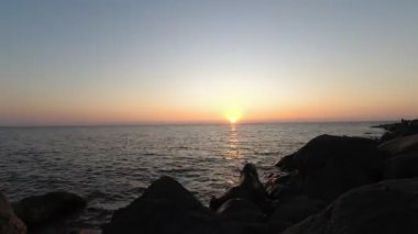 Denizde güneşli güzel bir gün batımı. Sahildeki muhteşem yaz manzarası. Karadeniz 'de alevli günbatımı manzarası ve üzerindeki turuncu gökyüzü. Sakin dalgalarda muhteşem güneş ışığı yansıması..