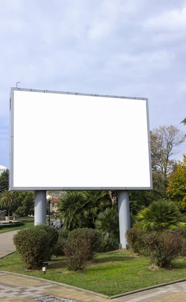 Electronic Billboard. Blank street billboard poster in the park on the background of tropical plants.