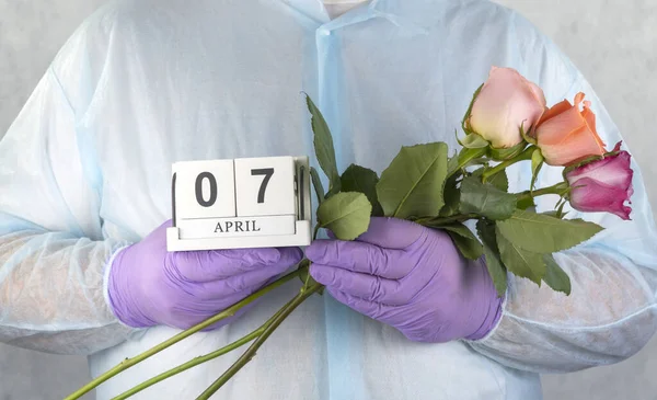 doctor with a bouquet of flowers in his hands. medical worker in surgical gown and medical gloves. Close- up of a bouquet of beautiful roses, doctors day. World Health Day April 07