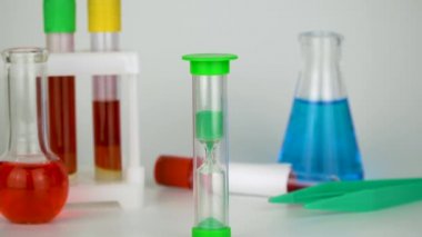  Kum saatini çeviriyorum. Coronavirus üzerinde çalışıyorum. İçinde virüs molekülleri olan kimyasal bir şişe. Kovid 19 için kan örneğiyle dolu tüpler. Tıp ve farmakoloji alanında araştırma. 