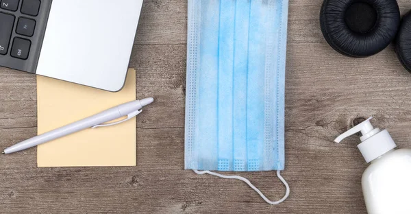 hygiene in the office. remote work kit on wooden desk. sanitizer gel and face mask, a solution against the spread of virus for quarantined employees. top view.