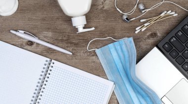 Ofiste hijyen var. Salgın koronavirüs COVID 19, kendini izole etme. Tahta masadaki uzaktan kumanda seti. Dezenfektan jeli ve yüz maskesi, karantina altındaki istihdam için virüsün yayılmasına karşı çözüm.