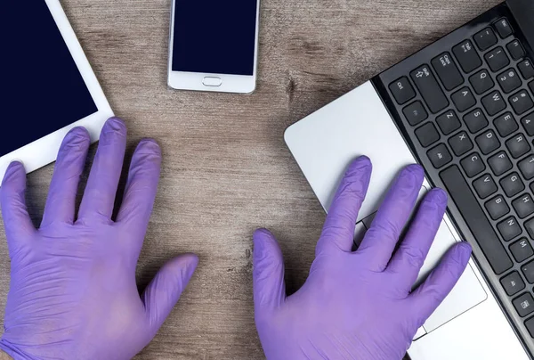 hands in medical gloves on the keyboard. Learning or working online in period of quarantine coronavirus COVID-19. Remote work. preventing the spread of a pandemic, stay at home, self-isolation.