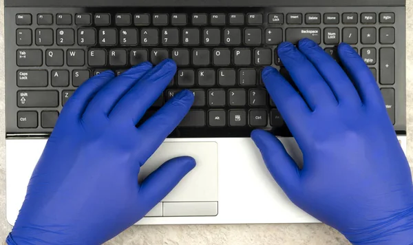 hands in medical gloves on the keyboard. Learning or working online in period of quarantine coronavirus COVID-19. Remote work.