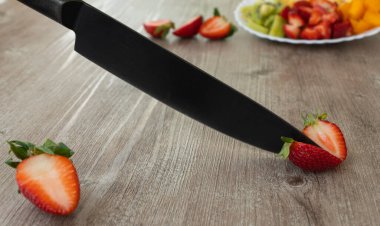 Meyve salatası bıçağıyla taze çilek kes. Sağlıklı ve besleyici kahvaltı, yemek hazırlama konsepti. Çilekler en zengin besin ve vitamin kaynağıdır. Seçici odak.