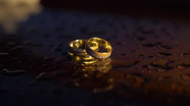 Bruiloft gouden ringen in rook en druppels water — Stockvideo