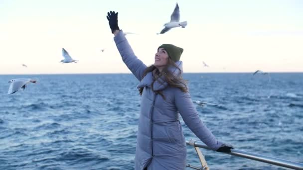 Fille dans une veste chaude entourée de mouettes — Video