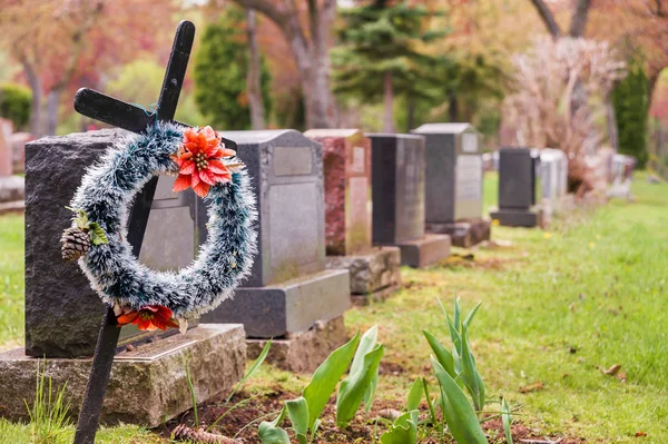 Corona funeraria con flores rojas en una cruz, en un cementerio . —  Fotos de Stock