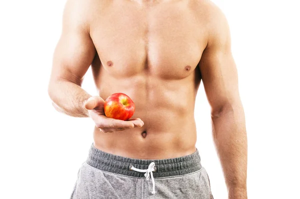 Muskulöser junger Mann mit einem Apfel auf weißem Hintergrund — Stockfoto