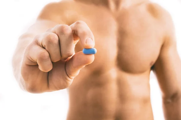 Muscoloso giovane uomo tenendo pillola blu isolato — Foto Stock