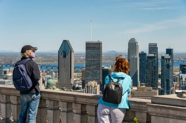 Montreal, CA - 18 Mayıs 2020: Coronavirüs salgını sırasında maskeli bir adam Royal Dağı 'nın tepesinden Montreal siluetine bakıyor