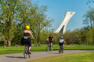 Montreal, CA - 22 Mayıs 2020: Covid 19 salgını sırasında Parc Maisonneuve 'de bisiklet süren insanlar. Arka planda Olimpiyat kulesi.