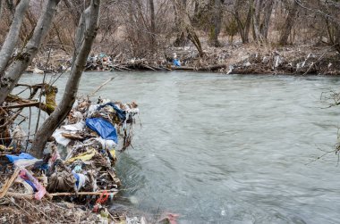 Çevre kirliliği. Plastik torbalar, şişeler, çöpler ve çöpler nehirde yüzüyor. Çöp ve su israfı.