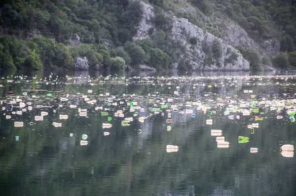 View on mountain lake, full of plastic garbage, floating rubbish and waste