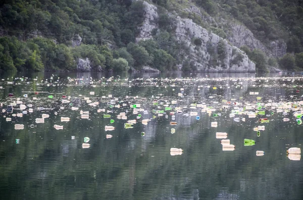 Dağ gölü manzarası, plastik çöpler, yüzen çöpler ve atıklarla dolu. 