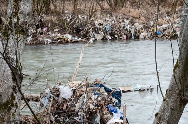 Çevre kirliliği. Plastik torbalar, şişeler, çöpler ve çöpler nehirde yüzüyor. Çöp ve su israfı.