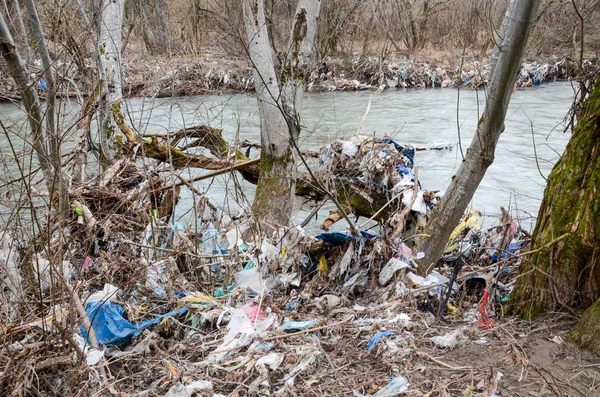 Çevre kirliliği. Plastik torbalar, şişeler, çöpler ve çöpler nehirde yüzüyor. Çöp ve su israfı.