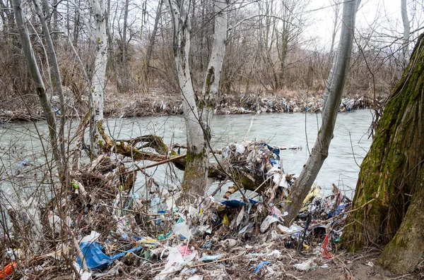 Çevre kirliliği. Plastik torbalar, şişeler, çöpler ve çöpler nehirde yüzüyor. Çöp ve su israfı.