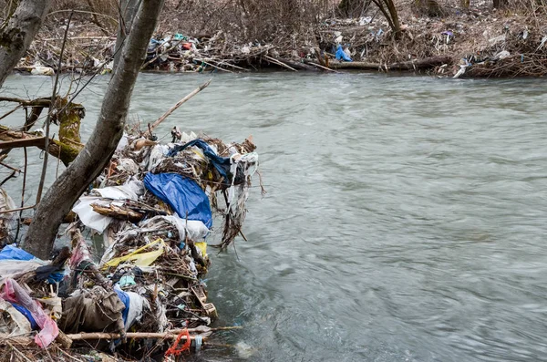 Çevre kirliliği. Plastik torbalar, şişeler, çöpler ve çöpler nehirde yüzüyor. Çöp ve su israfı.