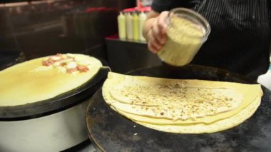 Kadın elektrikli ocakta krep yapıyor. Sokakta lezzetli yemekler hazırlıyorum..