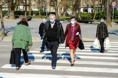 Bosna-Hersek 10 Nisan 2020: Yaya geçidinde yürüyen solunum maskeli insanlar, korona virüsü salgını