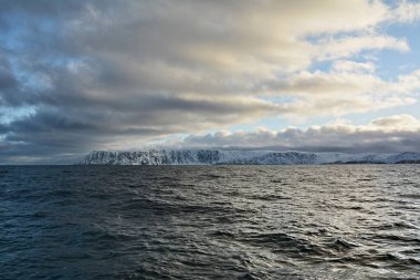 Norveç 'in Nordkapp belediyesi. Ülke, Avrupa 'nın en kuzey noktası olarak bilinen 307 metre yüksekliğindeki kayalıklardan oluşuyor. Avrupa 'nın en kuzeydeki noktası Cape Nordkinn' dir. Yelkenli tekneden karlı tepelere bak.