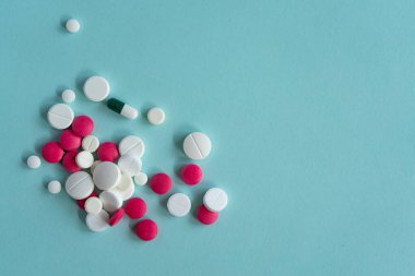 Mavi arka planda çeşitli şekillerde beyaz ve kırmızı haplar var. Coronavirus, tedavi, haplar, ilaç, salgın, virüs, hastalık. Mesaj için. Üst görünüm, alanı kopyala.