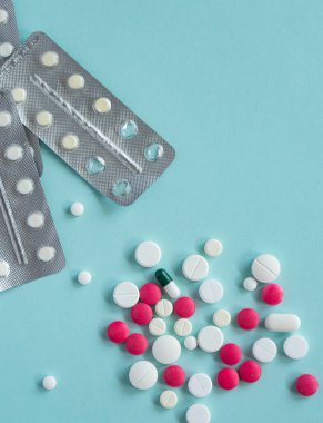 Placer, mavi arka planda çeşitli şekillerde çok renkli, beyaz ve pembe haplar. Tıbbi konsept. Eczane hastalığı tedavisi. Su toplamış tabletler. İlaç kapsülleri, sağlık için ilaçlar..