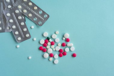 Placer, mavi arka planda çeşitli şekillerde çok renkli, beyaz ve pembe haplar. Tıbbi konsept. Eczane hastalığı tedavisi. Su toplamış tabletler. İlaç kapsülleri, sağlık için ilaçlar..