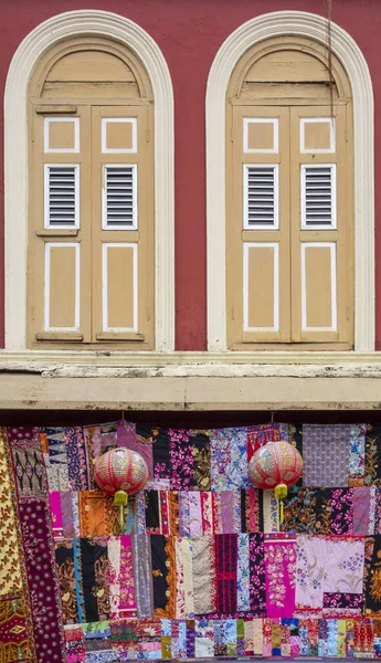 Fenêtres en bois contre le mur rouge avec une ceinture de courtepointe batik colorée — Photo