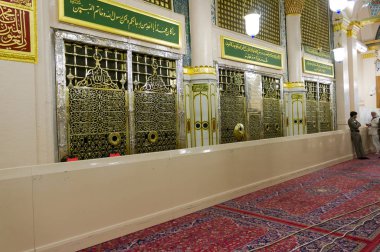 MEDINA, SAUDI ARABIA - CIRCA 2012 : A pilgrim make a prayer while the security police looks on at the gate of the burial chamber of Prophet Muhammad (pbuh) and his 2 companions.