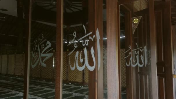 Statische Ansicht von Allah und dem Propheten Muhammad (a.s.) in arabischen Schriftzeichen, die auf das rotierende Glasfenster vor einer Moschee geschrieben sind.