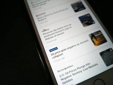 ILLUSTRATIVE EDITORIAL - CIRCA Nisan 2020: ham petrol fiyatlarındaki düşüşle ilgili haberlerde bir Apple iPhone 'un görüntüsü. The New York Times, Komonews, The Guardian ve Oilprice.com 'dan haberler.