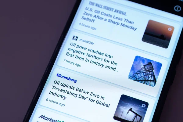 ILLUSTRATIVE EDITORIAL - CIRCA Nisan 2020: ham petrol fiyatlarındaki düşüşle ilgili haberlerde bir Apple iPhone 'un görüntüsü. The Wall Street Journal, MSNNow ve Bloomberg 'den haberler.