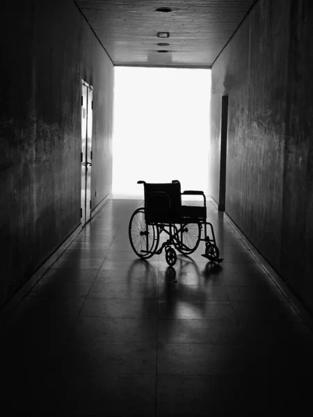 Low key images of an empty wheelchair in an empty hallway - sickness or loneliness in a hospital concept.