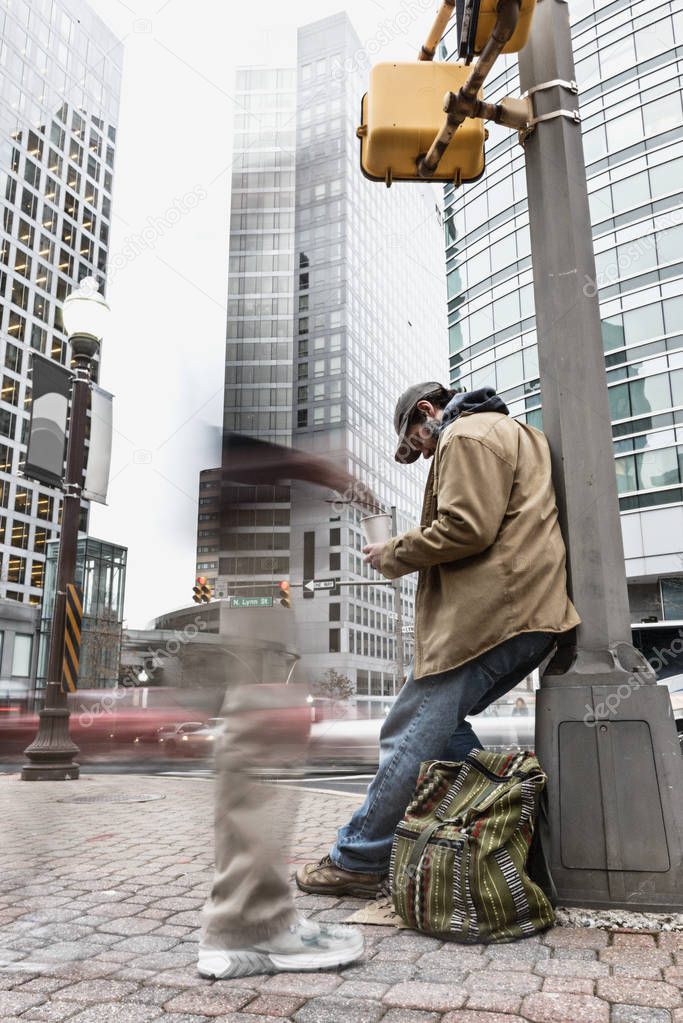 Panhandler receiving change from a pedestrian who is blurred by the use of long exposure