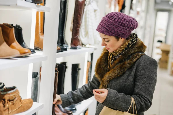 ブティックの靴店で靴のための冬服のショッピングで白人女性 ロイヤリティフリーのストック写真