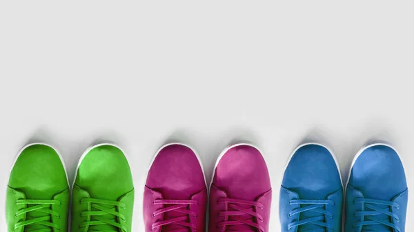 Група різнокольорових кросівок на білому тлі. Концепція - проблема з вибором кольорів взуття в сучасній індустрії, копія простору, плоска лінія — стокове фото