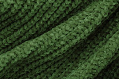 Dalgalar ve kıvrımlarla kabarık yeşil kumaş. Yumuşak pastel tekstil dokusu. Yumuşak bir kumaş üzerinde kıvrılır.