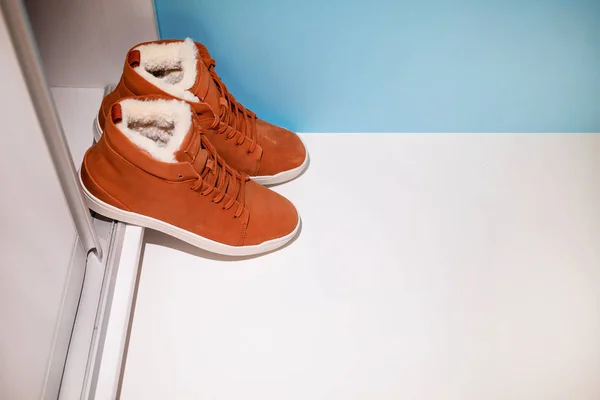 Zapatillas de deporte de invierno marrón de las mujeres están cerca del gabinete, la temporada de cambio de zapatos de verano para el invierno —  Fotos de Stock