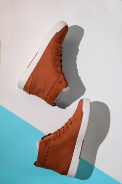 Mavi ve beyaz arka planda, Unisex kahverengi süet spor ayakkabılar, üst görünüm, düz döşeme, telif alanı