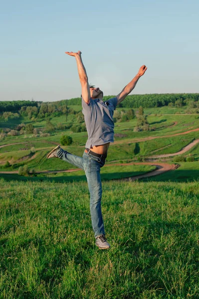 Un uomo in jeans e una maglietta in un salto. Il maschio è felice e libero nella natura — Foto Stock