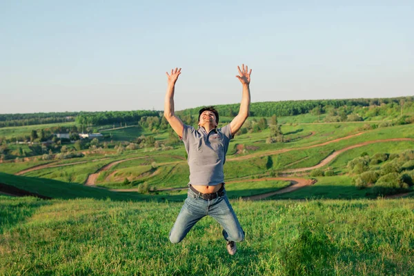 Un uomo in jeans e una maglietta in un salto. Il maschio è felice e libero nella natura — Foto Stock