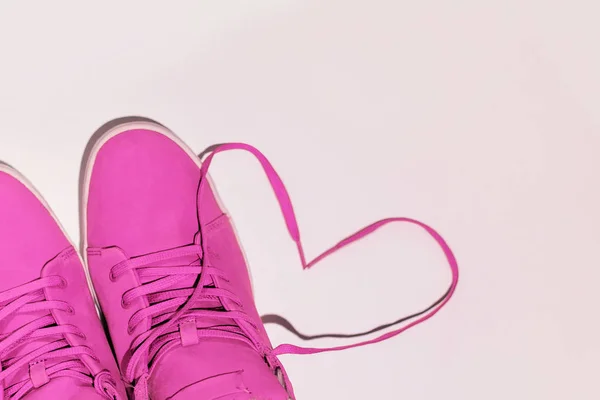 pink winter sneakers on a white and blue background. Heart made of shoe drawers. Concept - love for comfort, copyspase