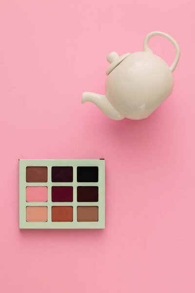 White teapot and makeup shadows on a pink background. Concept - daily trend makeup as a routine