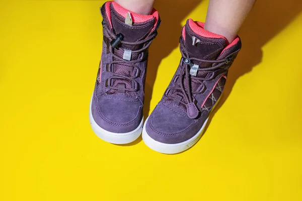 Sapatos de esportes de inverno de crianças roxas, eles são menina de sapatos. Botas confortáveis e de alta qualidade em um fundo amarelo — Fotografia de Stock