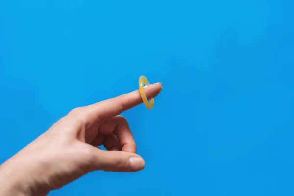 Condón en la mano sobre fondo azul — Foto de Stock