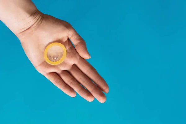 Preservativo na mão sobre fundo azul — Fotografia de Stock
