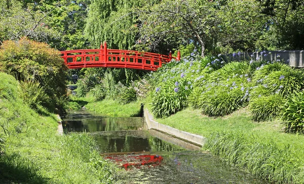 Красный японский мост через ручей — стоковое фото